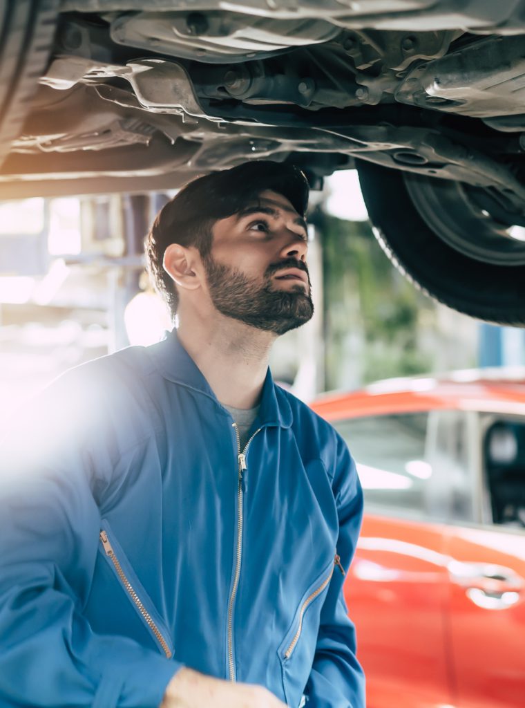 Mechanic checking underneath a vehicle during its MOT - MOT Ely